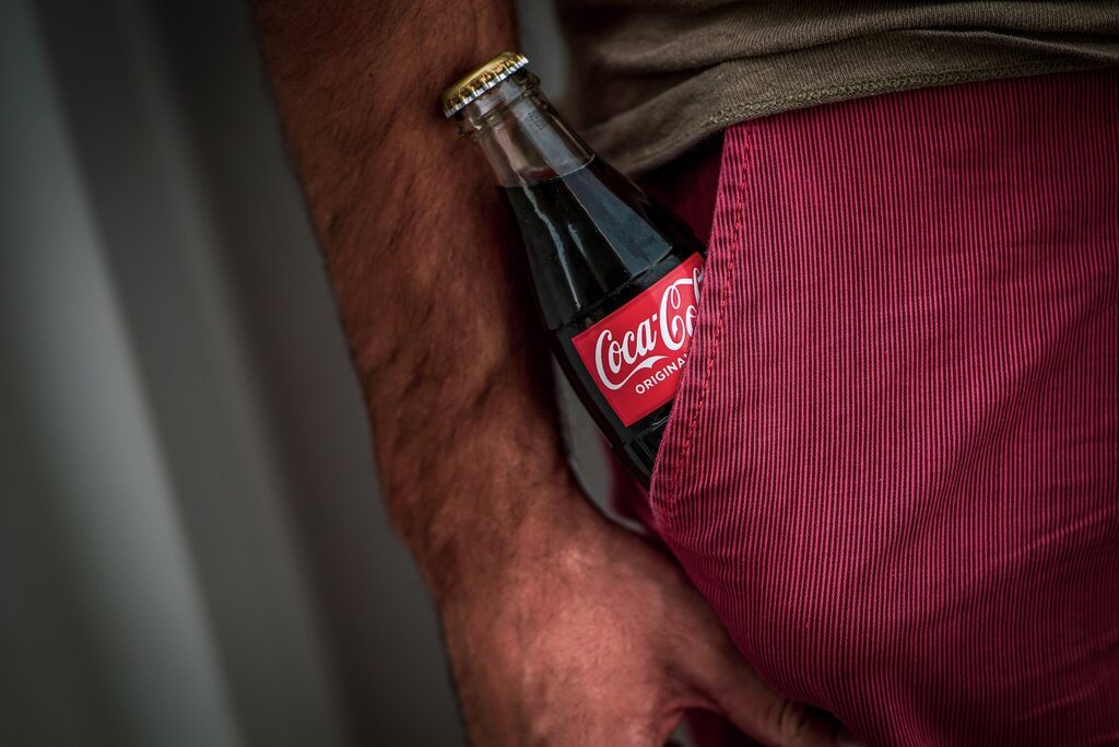 A coca-cola bottle in pant's pocket of a man which represent the brand equity value.