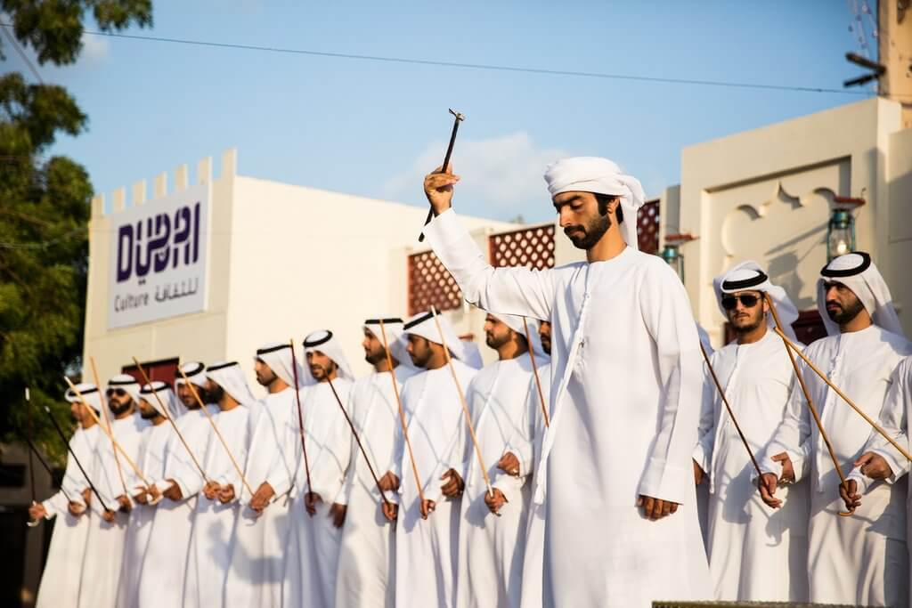 some of emiratis male are playing arabic dance and showing Dubai' culture and heritage sites.