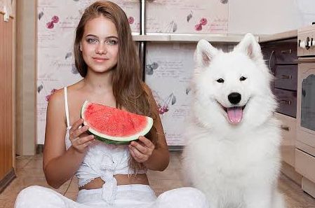   a girl sitting with dog and fruit in hand