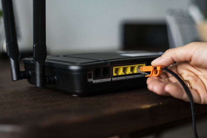 a man connecting LAN cable to a wireless modem